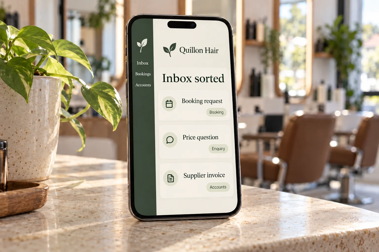 A phone on a salon counter showing a Quillon Hair sorted inbox concept