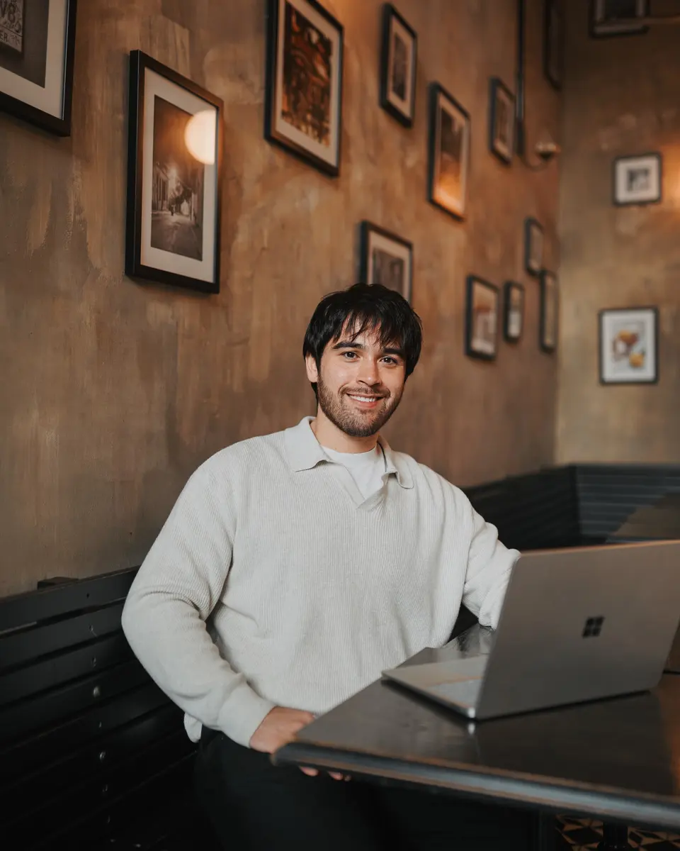 Reece, smiling at a table with his laptop