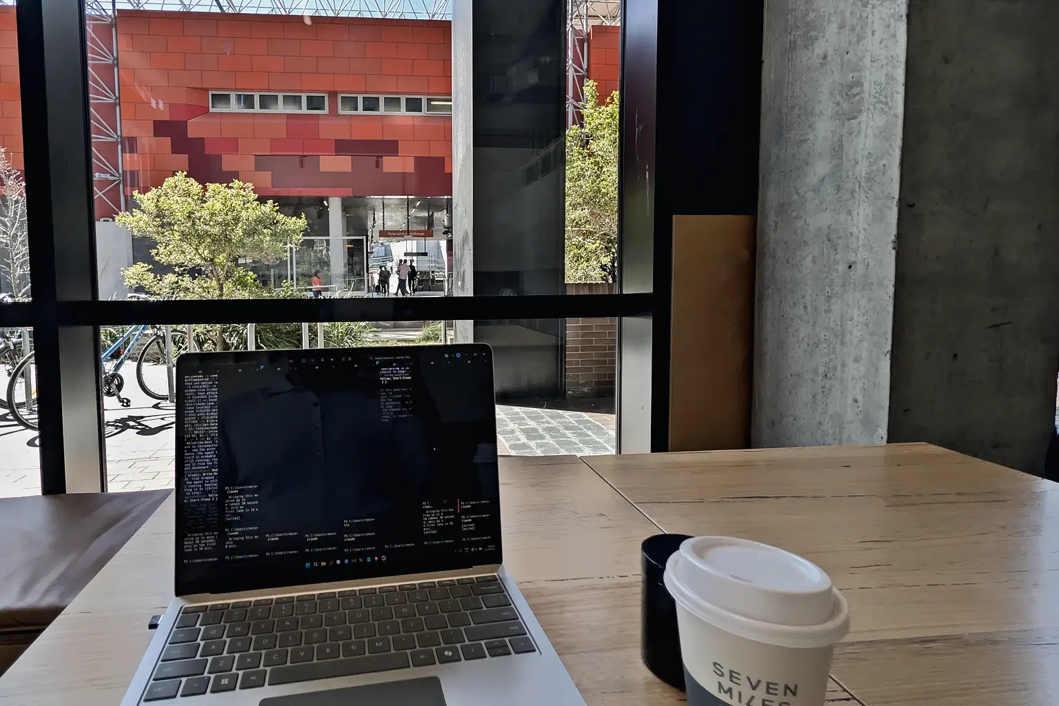 A laptop and coffee beside a window overlooking Newcastle