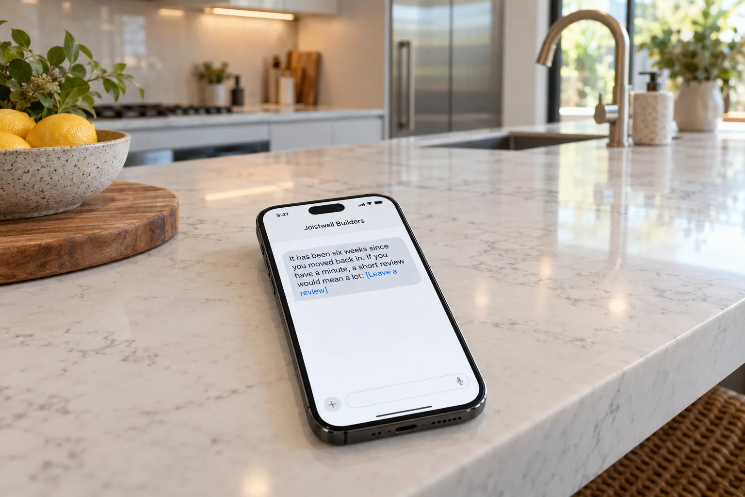 A phone in a renovated kitchen showing a Joistwell Builders review request message concept