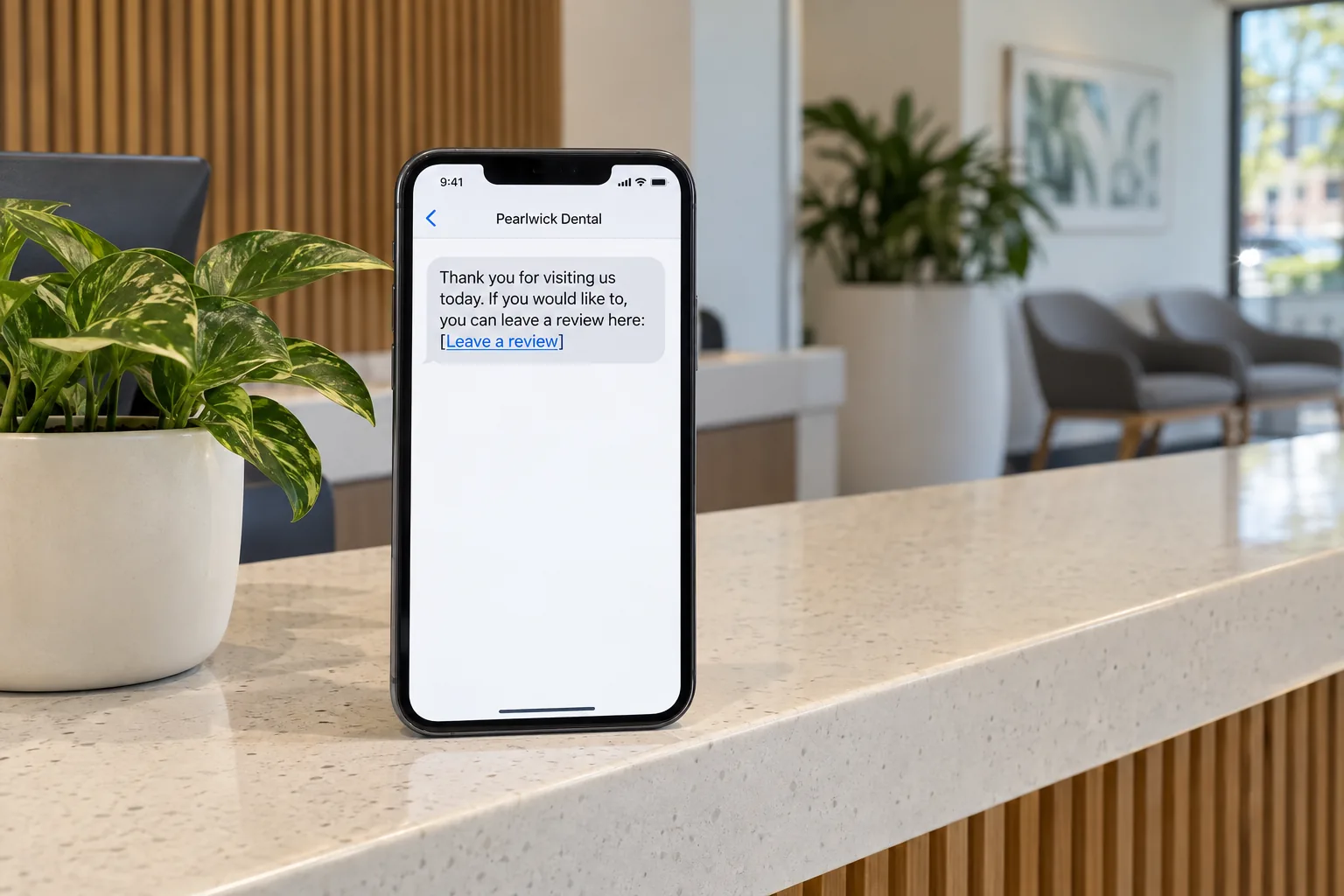 A phone on a clinic counter showing a Pearlwick Dental review request message concept