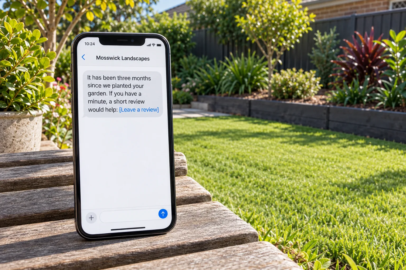 A phone on a garden bench showing a Mosswick Landscapes review request message concept