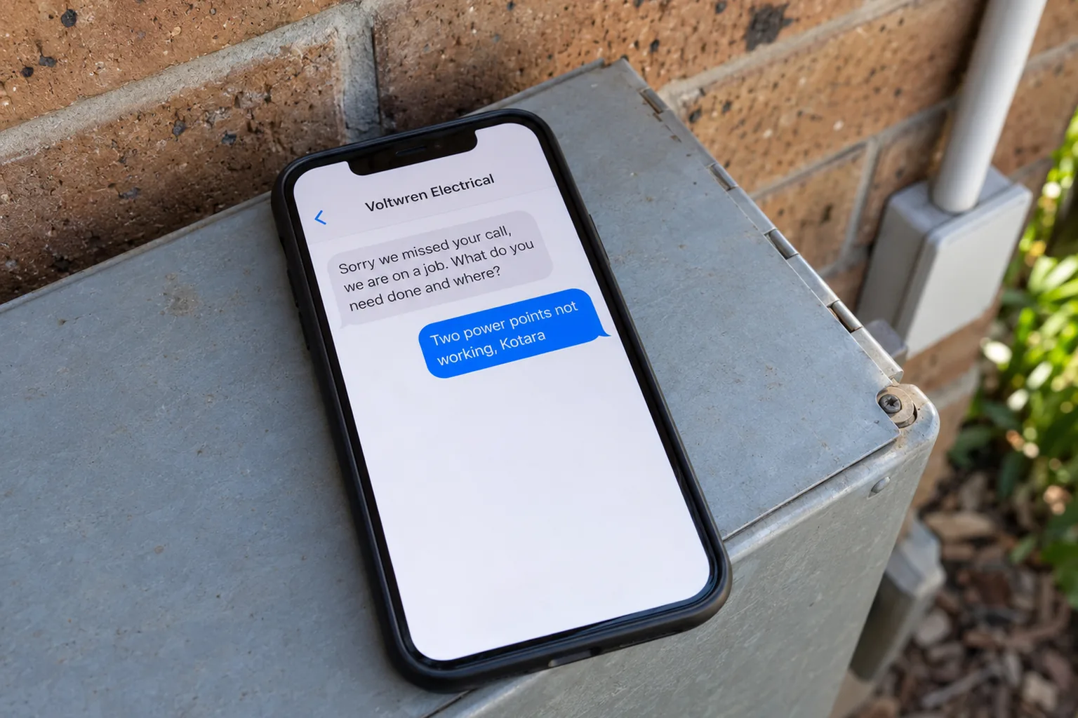 A phone on a switchboard cover showing a Voltwren Electrical missed-call text conversation concept