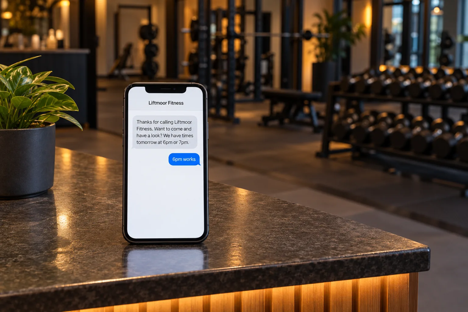 A phone on a gym front desk showing a Liftmoor Fitness missed-call text conversation concept